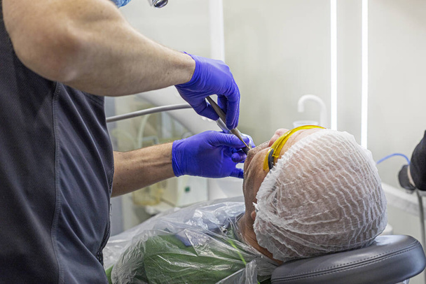 стоматолог вводит анестезию в больной зуб перед его лечением - Фото, изображение
