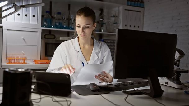 Valkoihoinen naistutkija analysoi asiakirjaa nykyaikaisessa laboratoriossa tieteellisten laitteiden ympäröimänä.. - Valokuva, kuva