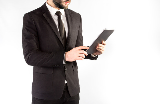 Hipster man in a classic suit isolated on a white background with a tablet in hand - Φωτογραφία, εικόνα