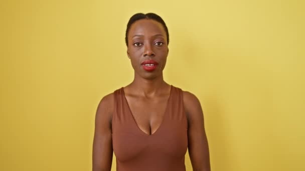 Afro-Amerikalı bir kadının şoke ve şaşkınlık içinde ağzı açık hayret dolu yüzü. Korkarak ve korkarak sarı arka planda, korku ve inançsızlığın bir karışımını sergileyerek. - Video, Çekim