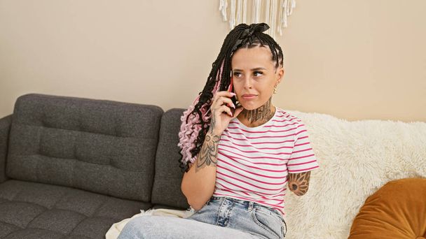 Измученная латиноамериканка, инвалид, зевающая во время разговора по телефону, скучающая в помещении, сидящая дома на диване - Фото, изображение
