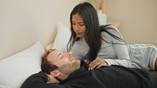 Hermosa pareja acostada en la cama mirando mientras duerme en el dormitorio - Foto, imagen