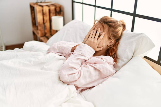 Νεαρή καυκάσια γυναίκα στρεσαρισμένη ξαπλωμένη στο κρεβάτι στο υπνοδωμάτιο - Φωτογραφία, εικόνα