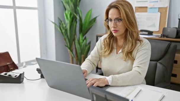 Spaanse zakenvrouw voelt zich gestrest en moe tijdens het werken op laptop in een moderne kantooromgeving - Video