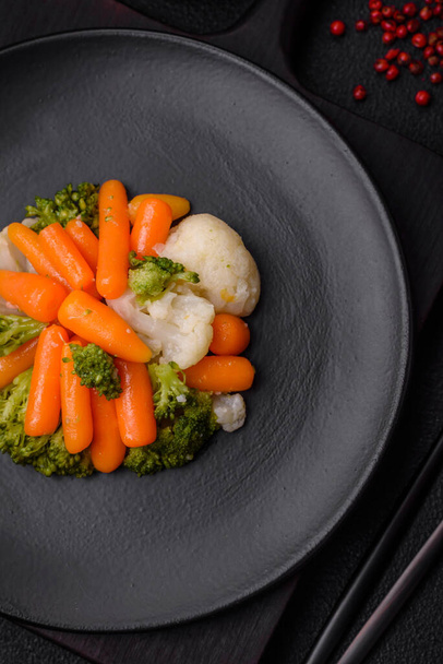Смачні свіжі овочі броколі, цвітна капуста, морква на пару з сіллю, спеціями та травами на звичайному фоні - Фото, зображення
