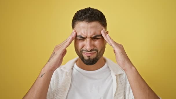 Stresli genç Arap adam sarıda tek başına dikilip migren ağrısıyla başını sıkıca tutuyor. Acı onun yakışıklı yüzünü kaşındırıyor. - Video, Çekim