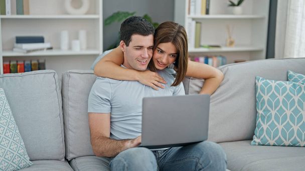 Krásný pár objímání navzájem pomocí notebooku usměvavý doma - Fotografie, Obrázek
