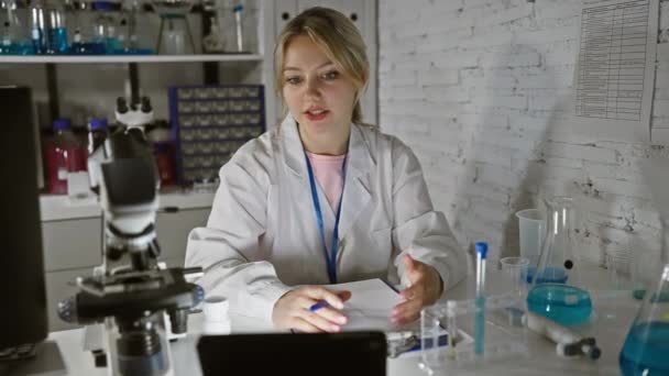 Una joven científica enfocada lleva a cabo investigaciones en un laboratorio moderno, examinando muestras y discutiendo hallazgos. - Imágenes, Vídeo