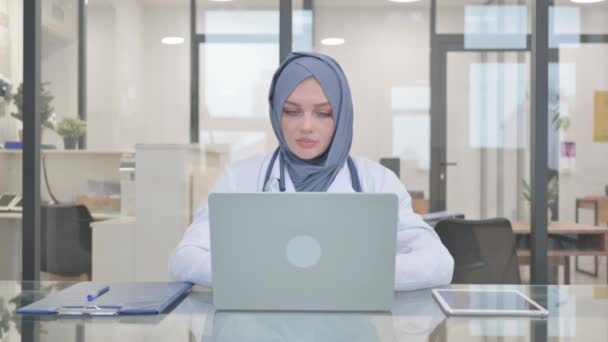 Médecin dans Hijab secouant la tête dans l'approbation tout en travaillant sur ordinateur portable - Séquence, vidéo