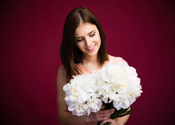 Smiling charming woman holding flowers  - Zdjęcie, obraz