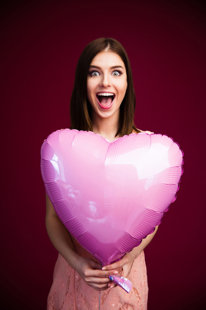 Surprised woman holding heart shaped balloon - Foto, Bild