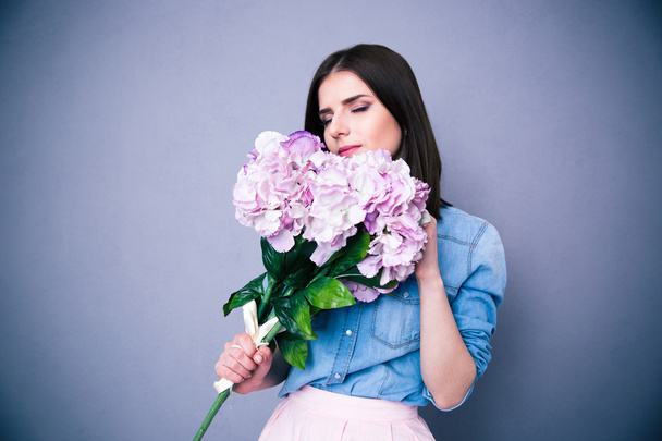 Young beautiful woman smelling flowers  - Fotó, kép