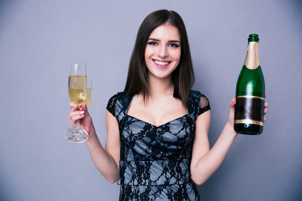 Smiling woman holding two glass and bottle of champagne - Φωτογραφία, εικόνα
