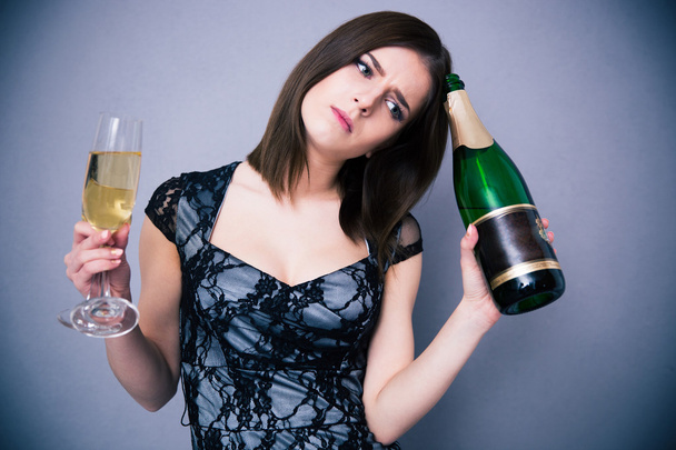 Pensive woman holding two glass and bottle of champagne - Фото, зображення