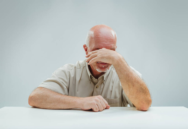 Sedící starší s rukou přes tvář vykazuje viditelné známky úzkosti nebo hluboké rozjímání - Fotografie, Obrázek