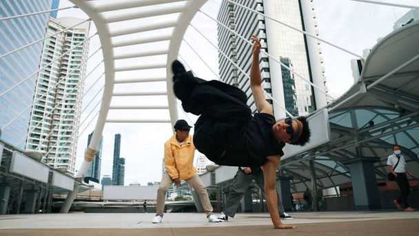 Bir grup profesyonel sokak dansçısı neşelen Asyalı hippi şehirde serbest dans ederken düşük açılı kamerayla çevrili insanlar tarafından. Break dans konsepti. Açık hava sporu 2024. Yumuşak bir şekilde.. - Fotoğraf, Görsel