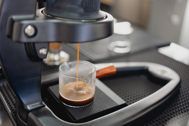 Kuuma espresso kaadetaan kahvinkeittimestä. Ammattimainen kahvinvalmistus - Valokuva, kuva