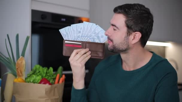 zbliżenie wideo przystojny młody mężczyzna z portfelem pełnym gotówki w domu kuchnia - Materiał filmowy, wideo