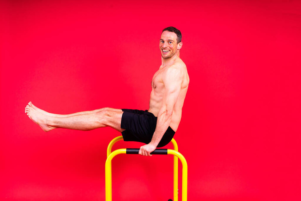 Gymnaste masculin exécutant handstand sur un bar parallèle, plan studio - Photo, image