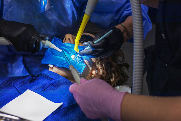 стоматолог і помічник в рукавичках лікують болісні зуби підлітка. Стоматологічна допомога та здоров'я - Фото, зображення