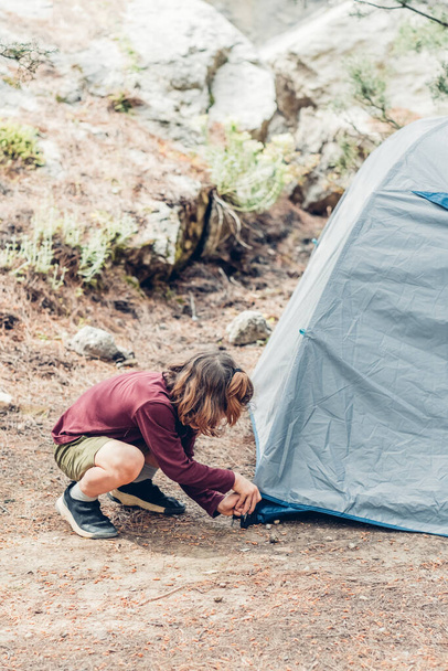 Słodki chłopak ustawia namiot turystyczny. Podróże letnie, kamping i turystyka koncepcja. Turystyka ekologiczna. - Zdjęcie, obraz