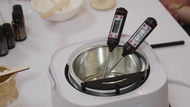 misurare la temperatura della cera di cocco fusa in un bagno d'acqua, facendo candele. Filmati 4k di alta qualità - Filmati, video
