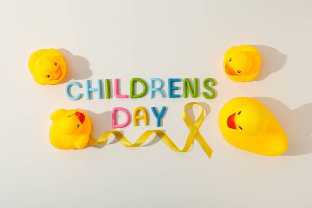 La inscripción Día del Niño con una cinta amarilla y un pato de juguete - Foto, imagen