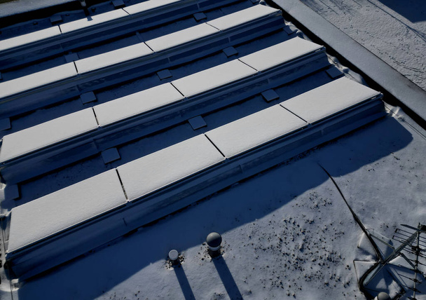 le chauffage de l'eau dans les collecteurs sur les toits à pignon et plats fonctionnent lorsque le soleil brille. givre recouvert d'une couche de neige ou de givre doit être plâtré, sinon l'efficacité sera recuced dans la silhoulette blanche rangée - Photo, image
