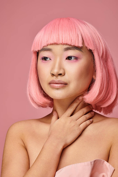 portrait of pretty young asian woman with pink hair looking to side against vibrant background - Φωτογραφία, εικόνα