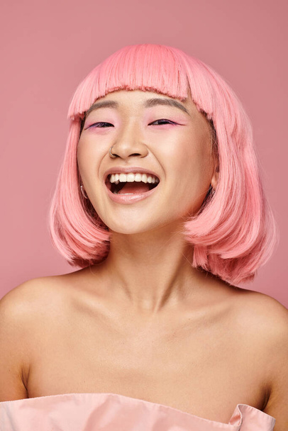 pretty young woman with pink hair and makeup laughing against vibrant background - Foto, imagen