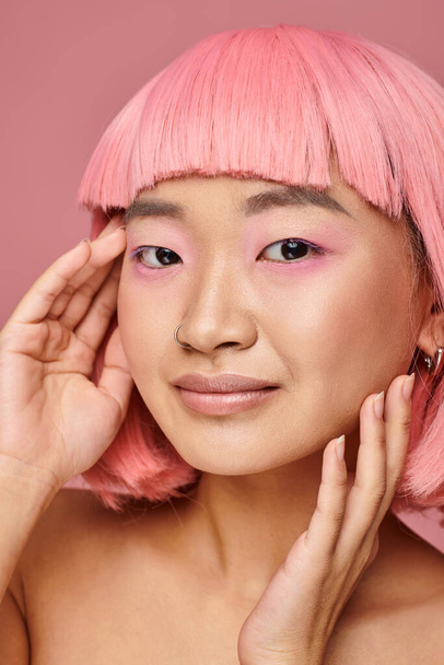lovely asian young woman with pink makeup posing with hands against vibrant background - Foto, afbeelding