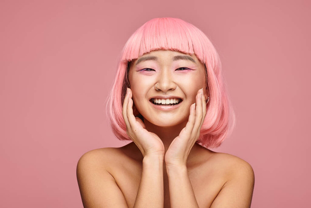 pretty asian young woman with pink hair laughing with hands against vibrant background - Photo, Image