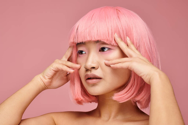 profile of beautiful asian woman in 20s with pink hair posing with hands against vibrant background - Photo, Image