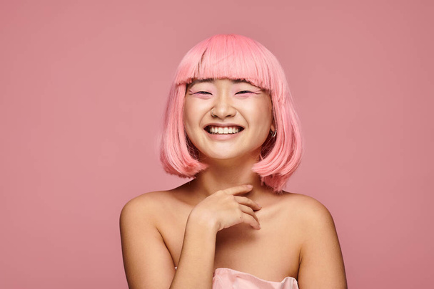 happy asian young woman with pink hair and makeup laughing against vibrant background - Fotografie, Obrázek