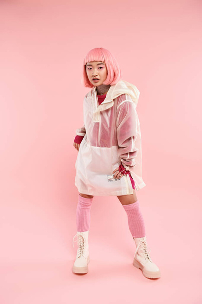 confident asian woman in her 20s with pink hair in stylish outfit posing on vibrant background - Foto, immagini