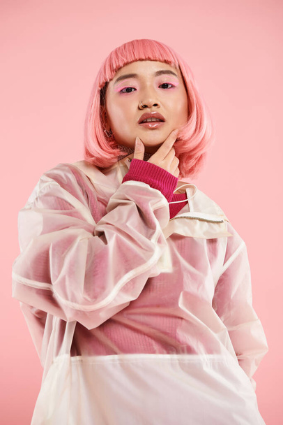 beautiful asian woman in 20s with pink hair and makeup touching chin against vibrant background - Photo, Image