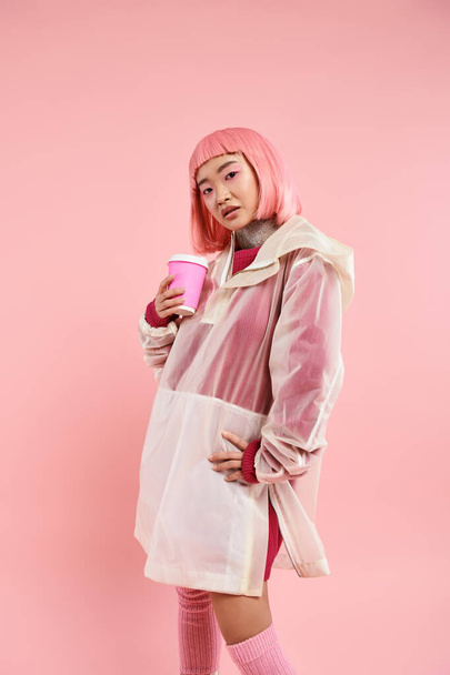 bastante asiático joven mujer con rosa pelo posando con café taza en vibrante fondo - Foto, Imagen