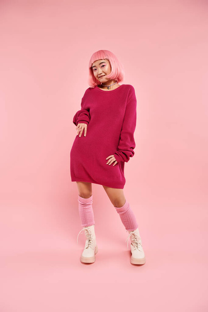 playful asian young woman with pink hair and makeup in stylish outfit posing on vibrant background - Foto, afbeelding