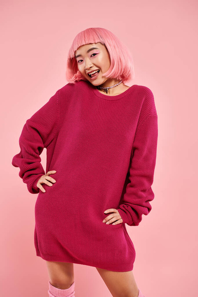 lovely asian woman with pink hair and makeup in stylish outfit posing against vibrant background - Photo, image