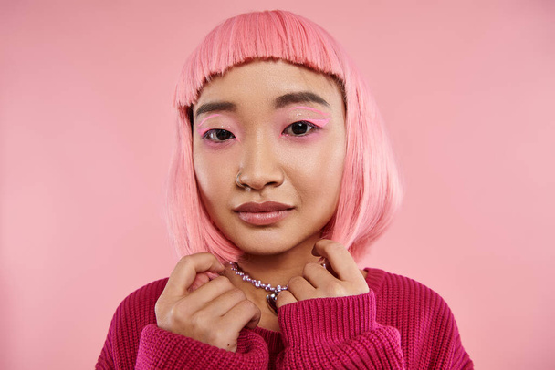 zblízka krásné asijské mladé ženy s perleťovým náhrdelníkem, růžové vlasy a make-up při pohledu do kamery - Fotografie, Obrázek