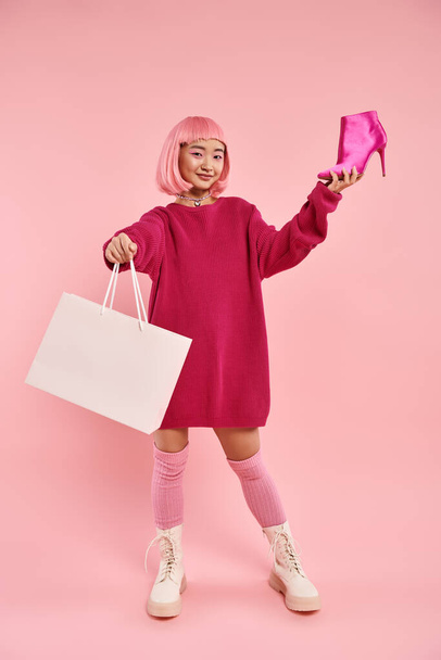 okouzlující asijské žena v ní 20s s šťastný úsměv hrdý na její nákup na růžovém pozadí - Fotografie, Obrázek