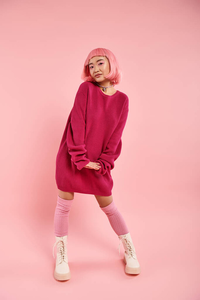 charming asian young girl in vibrant sweater outfit cute posing on pink background - 写真・画像