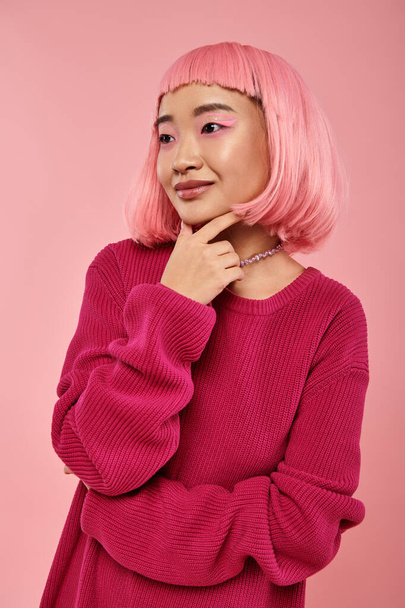attraktive junge Frau mit rosa Haaren umrahmt Kinn mit Hand vor lebendigem Hintergrund - Foto, Bild