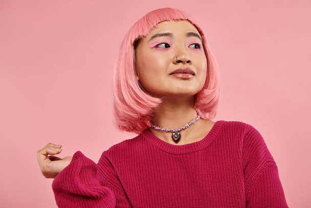 charmante aziatische jonge vrouw met parel ketting en roze haar op zoek naar kant op levendige achtergrond - Foto, afbeelding