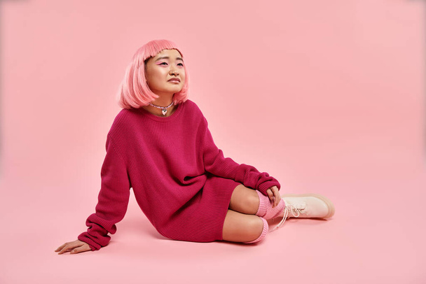mooie aziatische jong meisje met roze haar en make-up zitten en dromen op levendige achtergrond - Foto, afbeelding