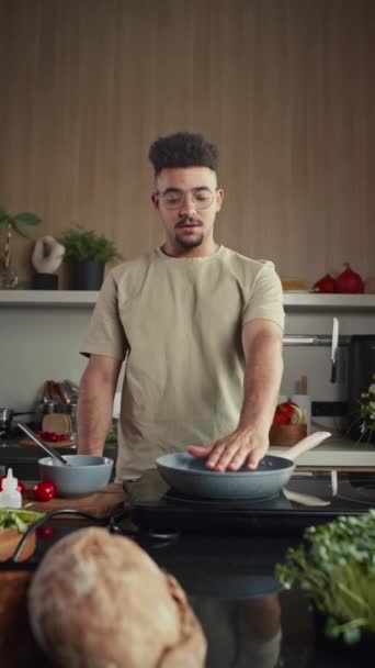 Plan vertical du blogueur culinaire versant des œufs sur une poêle chaude et disant comment faire cuire l'omelette à la caméra tout en filmant la recette du petit déjeuner pour les médias sociaux à la maison - Séquence, vidéo