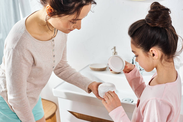 A brunette woman lovingly assists her preteen daughter in a modern bathroom during their beauty and hygiene routine. - Foto, Imagen