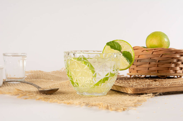 Кайпіньї склянка коктейлю Pinga з лимоном на гладкому білому тлі перед фотографією - Фото, зображення