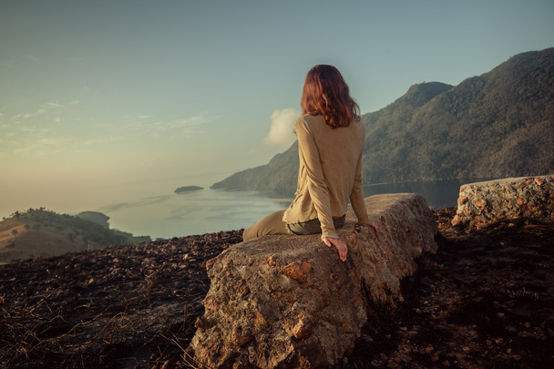 Femme assise sur un rocher insolite au lever du soleil
 - Photo, image