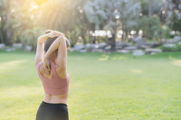 Obejmij zdrowy tryb życia wellness z tylnym portretem Azjatki po 30-tce w różowej odzieży sportowej, oddychając świeżym powietrzem i przygotowując ciało przed bieganiem po parku o zachodzie słońca. koncepcja zewnętrzna sprawności - Zdjęcie, obraz